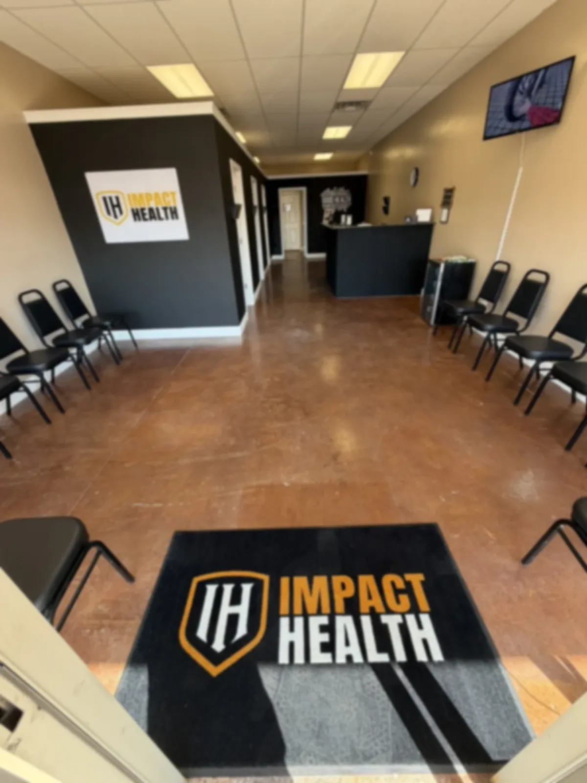 Impact Health Corinth lobby, branded floor mat, waiting chairs, and welcome desk